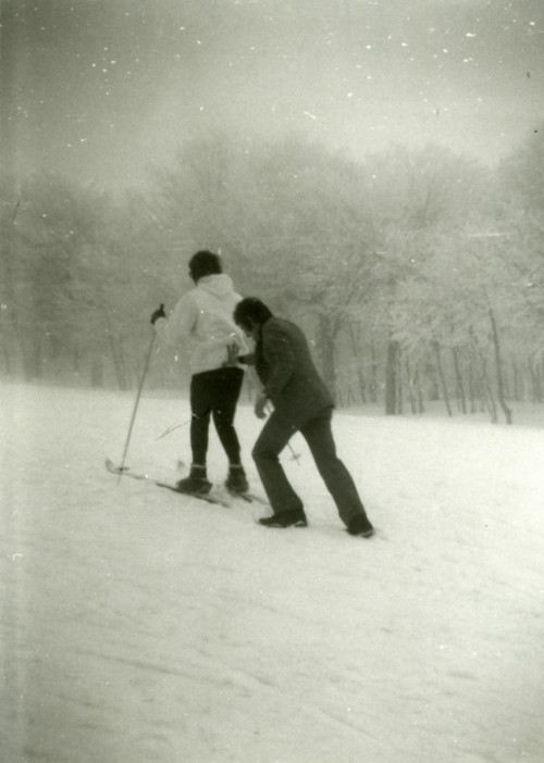 Uomo che spinge uno sciatore in salita sulla neve