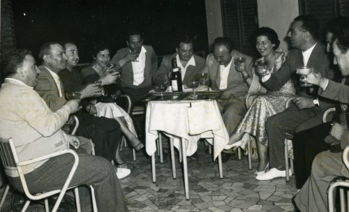 Nove uomini e due donne brindano a tavola