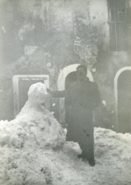 Angelo Rocchi si poggia a un pupazzo di neve per le vie del paese