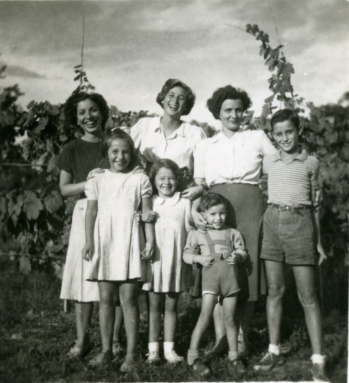 Diva Compagnucci con due donne, due bambine e due bambini sorridenti in campagna davanti alle viti