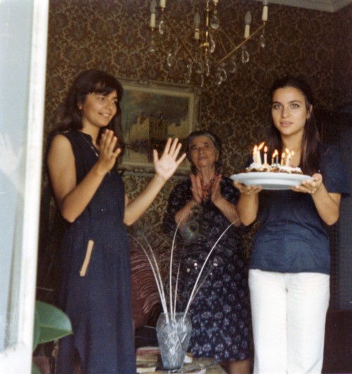 Elena Rocchi porta una torta con le candeline, mentre Elda Rocchi e una signora applaudono