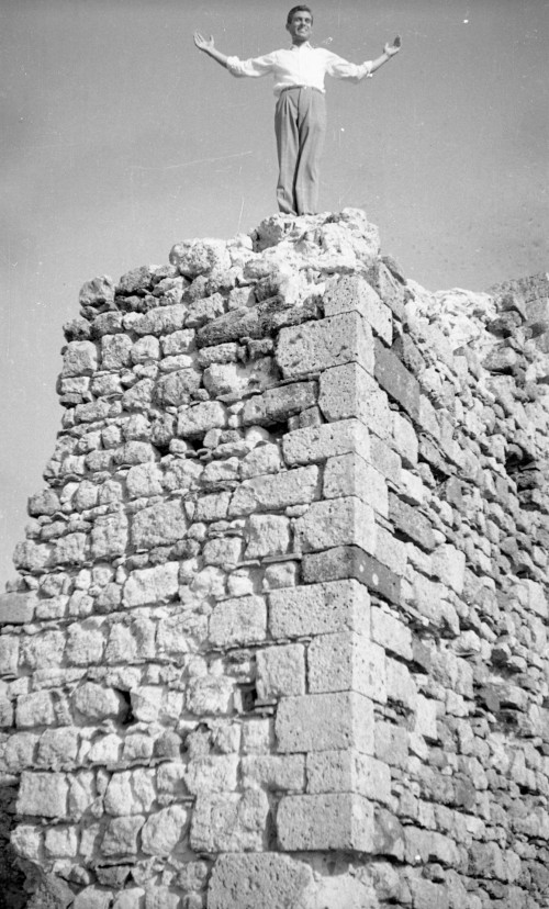 Uomo in piedi con le braccia aperte sorpra la torre della Rocca dei Frangipane