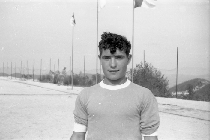 Ragazzo al campo da calcio con alle spalle le bandiere