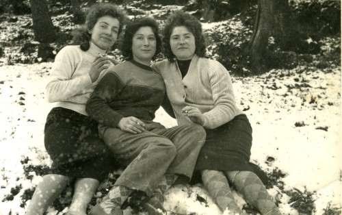 Tre ragazze sedute sulla neve con una sigaretta in mano