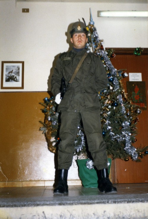 Militare in divisa con alberi di Natale sullo sfondo